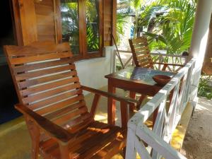 two wooden chairs and a table on a porch at Gems Garden Guest House in Tangalle