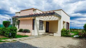 a small white house with a driveway at Swara Ranch Nanyuki in Nanyuki