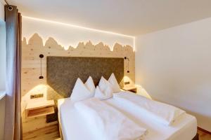 1 dormitorio con cama blanca y almohadas blancas en Hotel Residence Gasser, en Villandro