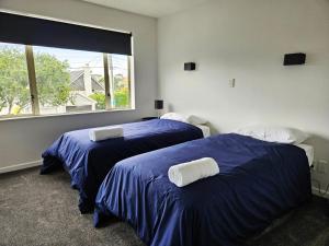 two beds in a room with a window at Spacious and Luxury, City Fringe Bliss! in Wellington