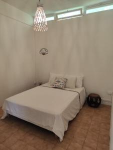a bedroom with a white bed and a chandelier at La petite Maison de La Saline-les-Bains in Saint-Paul