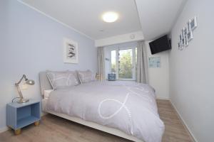 een witte slaapkamer met een bed en een raam bij TRAUM FeWo Strandliebe mit Meerblick, 3 Schlafzimmer, 2 Bäder in Binz