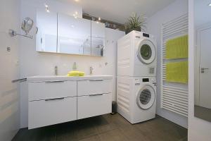 eine weiße Küche mit einer Waschmaschine und einem Waschbecken in der Unterkunft TRAUM FeWo Strandliebe mit Meerblick, 3 Schlafzimmer, 2 Bäder in Binz