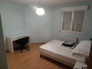 a bedroom with a bed and a desk and a window at Le plein soleil in Cornimont