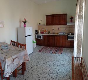 a kitchen with a table and a white refrigerator at Pitsinis Apartments I in Roda +5 photos