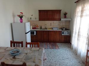 a kitchen with a table and a white refrigerator at Pitsinis Apartments I in Roda