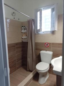 a bathroom with a toilet and a sink and a window at Pitsinis Apartments I in Roda