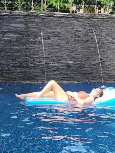 a woman in a bikini laying on a raft in the water at Mountain View Guest House in Phatthalung