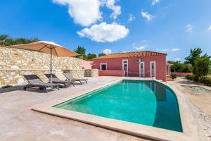 a pool with two chairs and an umbrella next to a house at Aelios Villa in Patitiri
