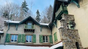 a house with green shuttered windows and snow on it at Villa Les Roches d'Yzeron in Yzeron