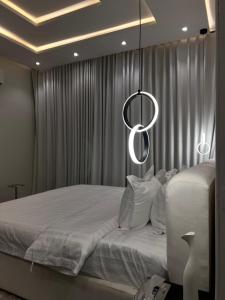 1 dormitorio con 1 cama blanca grande con lámpara de araña en شقه فندقيه فاخرة, en Riad