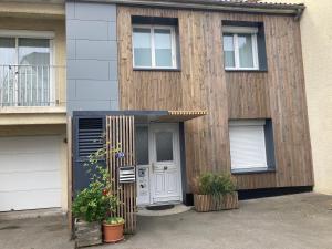 une maison avec une porte et deux plantes devant elle dans l'établissement Appartement cosy, à Saint-Sébastien-sur-Loire