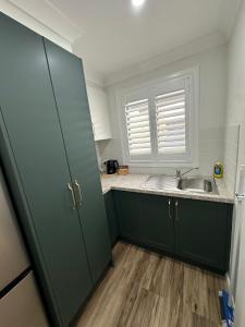 a kitchen with green cabinets and a sink and a window at Central Evans Wagga Apartments in Wagga Wagga