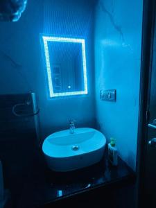 La salle de bains bleue est pourvue d'un lavabo et d'un miroir. dans l'établissement Djourney Hospitalities 1BF2, à Thākurdwari
