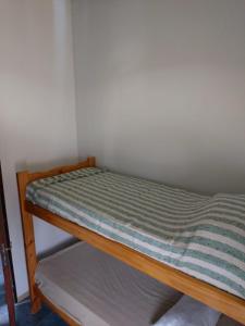 Una cama pequeña con una sábana rayada. en La Peninsula en Neuquén