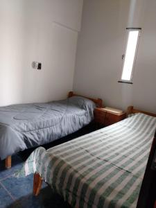 2 camas en una habitación pequeña con ventana en La Peninsula en Neuquén