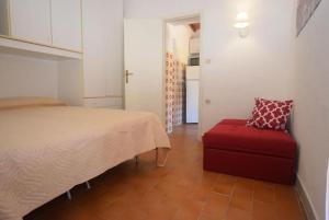 1 dormitorio con 1 cama y 1 maleta roja en Appartamenti Seccheto en Seccheto