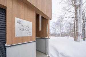 a sign on the side of a building in the snow at Yuki Usagi - walking distance to Rusutsu Resort in Rusutsu