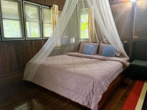 a bedroom with a bed with a mosquito net at Chaweang cozy house 1 km.Lotus in Ban Ko Khwan