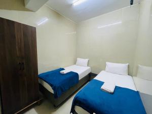 two beds in a small room with blue and white sheets at Hotel City Bukit Bintang in Kuala Lumpur