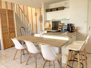 uma cozinha com uma mesa de madeira e cadeiras brancas em RÉF 383 - LORIENT Appartement duplex type 3 avec 2 parkings em Lorient
