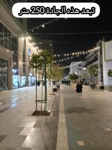 a city street at night with a tree in the middle at شقق جادة قباء in Medina