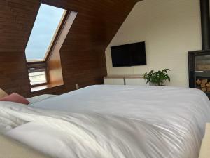 Schlafzimmer mit einem großen weißen Bett und einem Flachbild-TV in der Unterkunft Duplex Duinenhof in Bredene