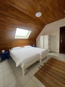 1 dormitorio con cama blanca y techo de madera en Duplex Duinenhof, en Bredene