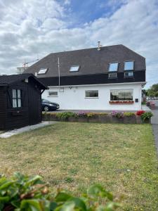 una casa blanca con techo negro y patio en Duplex Duinenhof, en Bredene