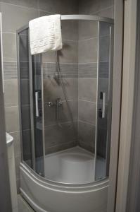 La salle de bains est pourvue d'une douche avec une porte en verre. dans l'établissement Floros simfonija Jūros, à Šventoji