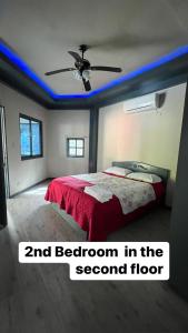 a bedroom with a bed with a red comforter and a ceiling at Heaven’s Gate Resort in Puerto Galera