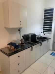 a kitchen with white cabinets and a black counter top at BEDONG GOLF VILLA in Bedung