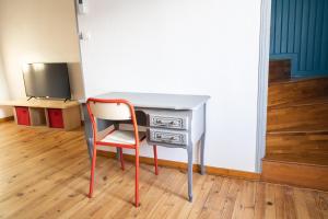 einen Schreibtisch mit Stuhl neben einem TV in der Unterkunft La Vigère in Mirefleurs