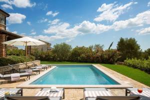 una piscina con sillas y sombrilla en Rustic Villa Rorripa with a pool in Istria, en Sveti Lovreč Pazenatički