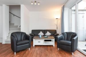 2 Stühle und ein Sofa im Wohnzimmer in der Unterkunft Ferienhaus Lachmöwe - Uns Huus an t Küst in Bensersiel