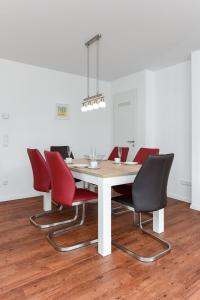ein Esszimmer mit einem Tisch und roten Stühlen in der Unterkunft Ferienhaus Lachmöwe - Uns Huus an t Küst in Bensersiel
