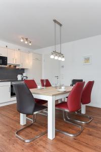 einen Esstisch mit roten Stühlen in der Küche in der Unterkunft Ferienhaus Lachmöwe - Uns Huus an t Küst in Bensersiel