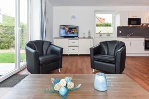 2 schwarze Stühle und ein Tisch im Wohnzimmer in der Unterkunft Ferienhaus Lachmöwe - Uns Huus an t Küst in Bensersiel