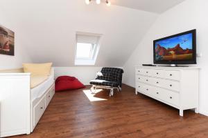 1 dormitorio con cama y vestidor con TV en Ferienhaus Gezeiten - Uns Huus an t Küst, en Bensersiel