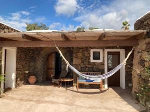 a hammock hanging from the outside of a stone house at Dammuso Faraglione del Fico d'India in Pantelleria