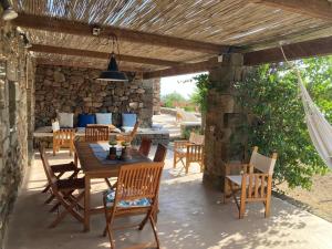 an outdoor patio with a wooden table and chairs at Dammuso Faraglione del Fico d'India in Pantelleria