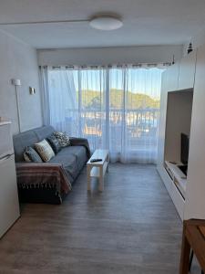 a living room with a couch and a large window at Studio vue port, parking privé, terrasse, clim in Le Grau-du-Roi