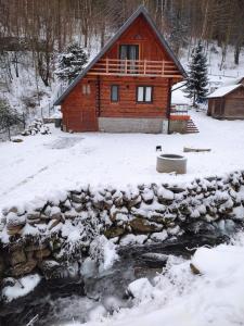 een blokhut in de sneeuw naast een beek bij Lawendowe wzgórze in Pieszyce