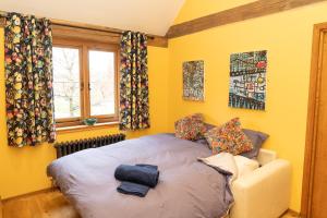 a bedroom with a large bed with yellow walls at Jossie's Snug in Bletchingley