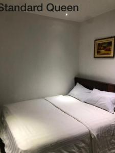 1 dormitorio con 1 cama con sábanas blancas en Hotel Vistana Micassa en Taiping