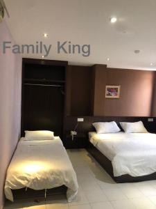 two beds in a hotel room with a family king sign at Hotel Vistana Micassa in Taiping