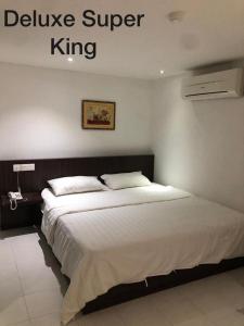 een slaapkamer met een groot bed met witte lakens bij Hotel Vistana Micassa in Taiping