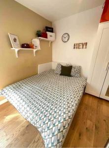 um pequeno quarto com uma cama com um relógio na parede em Cosy studio proche Paris em Villeneuve-Saint-Georges