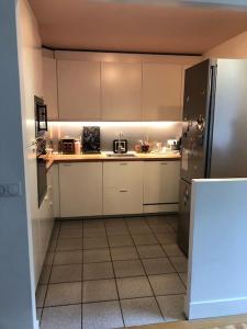 uma cozinha com armários brancos e um frigorífico preto em Maison familiale et lumineuse avec jardin em Versailles