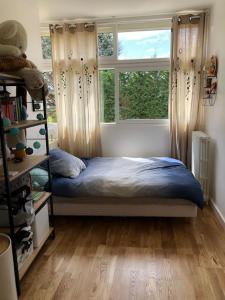 een slaapkamer met een bed voor een raam bij Maison familiale et lumineuse avec jardin in Versailles